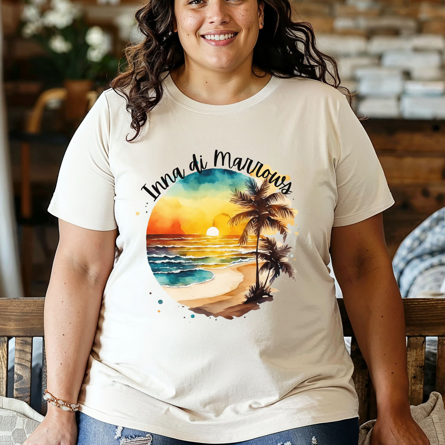 Woman wearing a t-shirt with a beach graphic and text, sitting on a wooden bench.