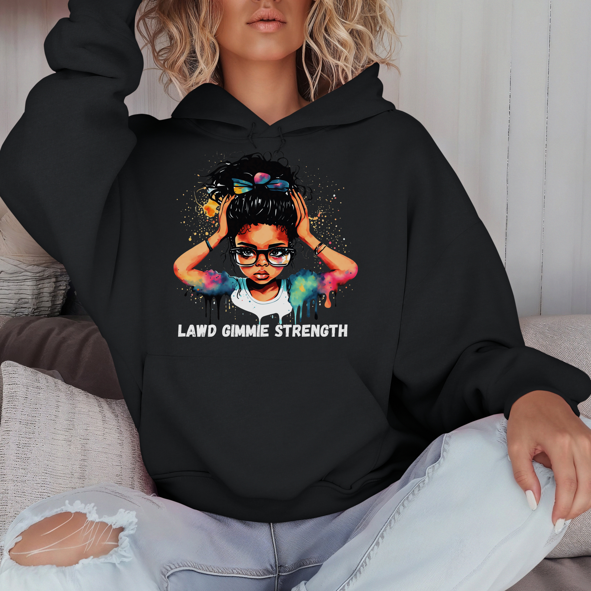 Person wearing a black hoodie with a graphic design and text, sitting on a couch.