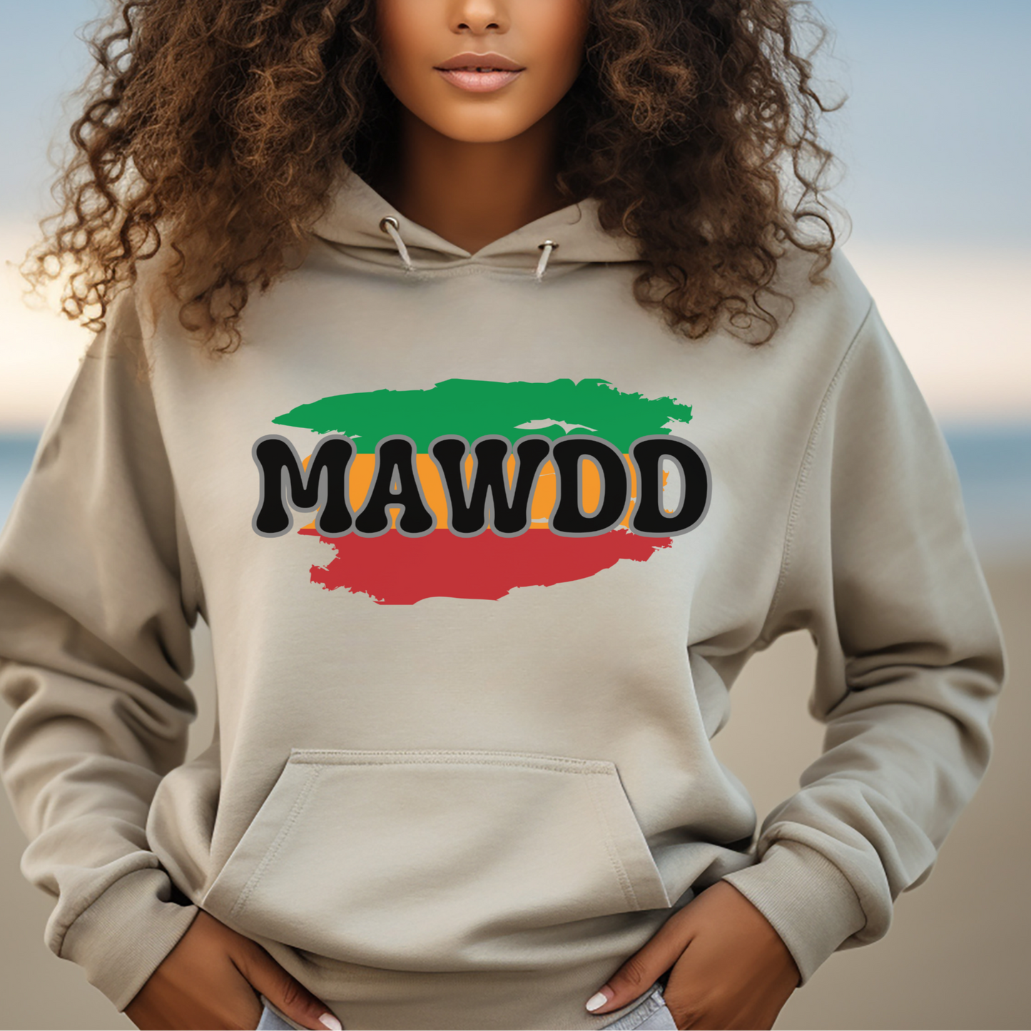Woman wearing a beige hoodie with 'MAWDD' design on a beach