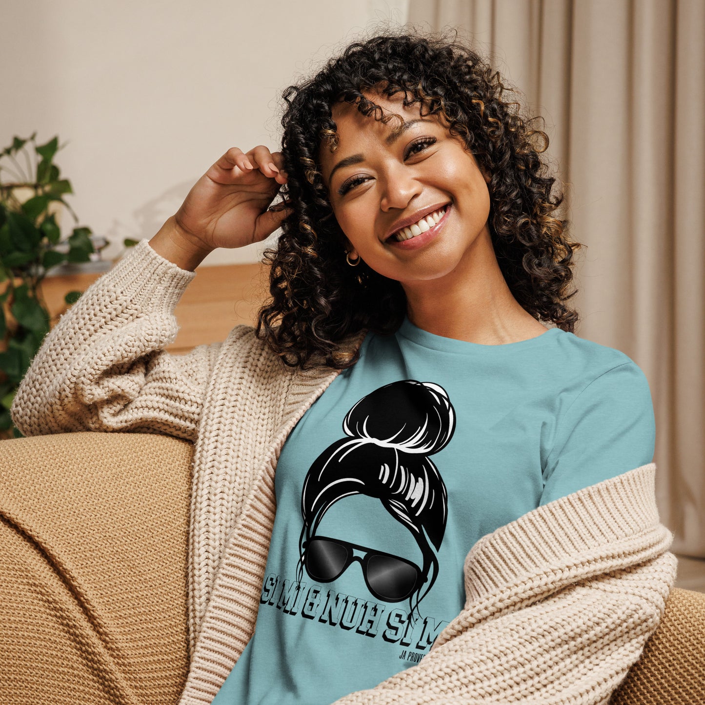 Woman wearing a blue t-shirt with a graphic design, sitting on a couch.