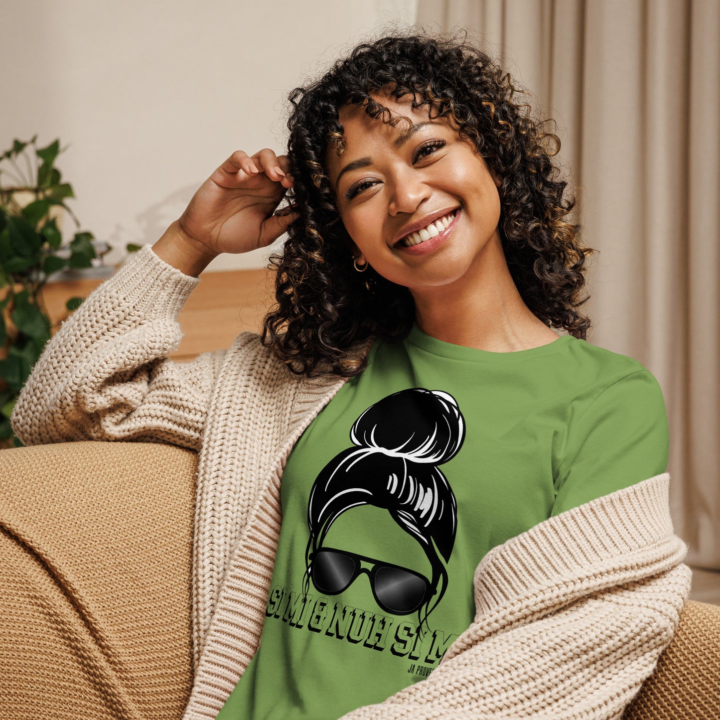 Woman wearing a green t-shirt with a graphic design, sitting on a couch.