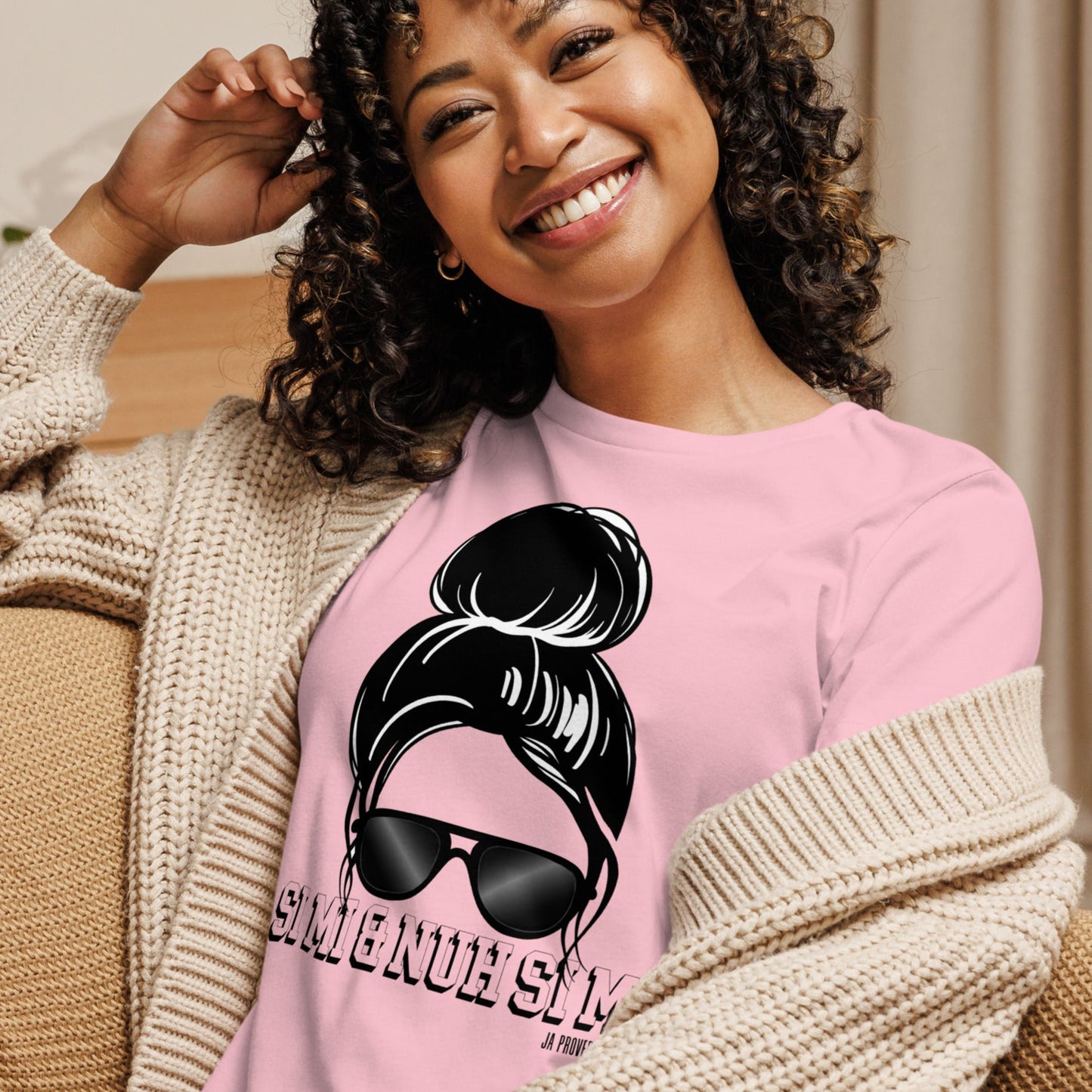 Woman wearing a pink sweatshirt with a graphic design, sitting on a couch.